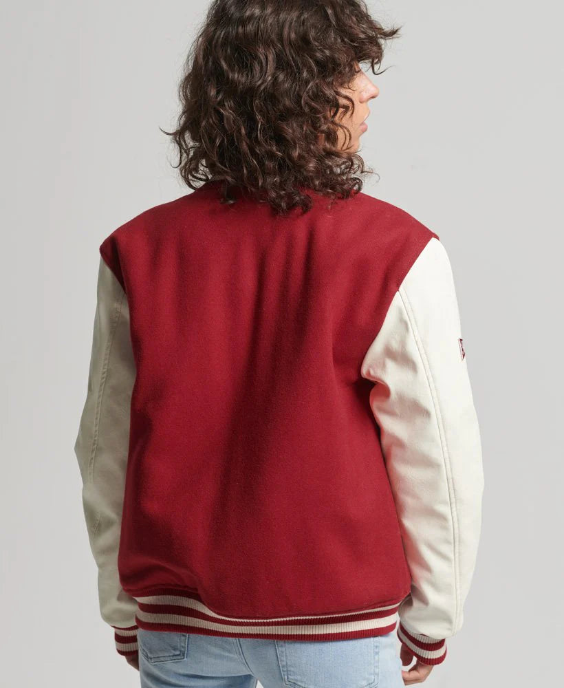 Person wearing a red and beige varsity jacket on a plain background