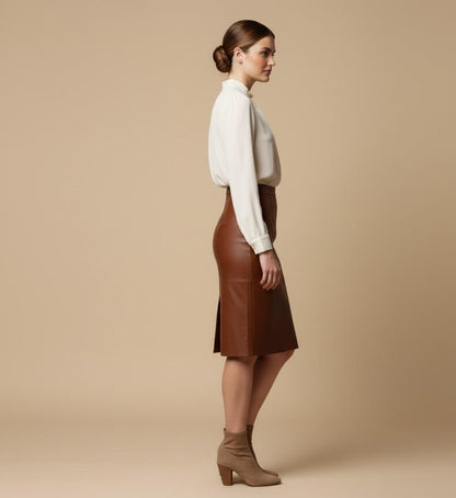 Woman wearing a white blouse and brown leather skirt against a beige background