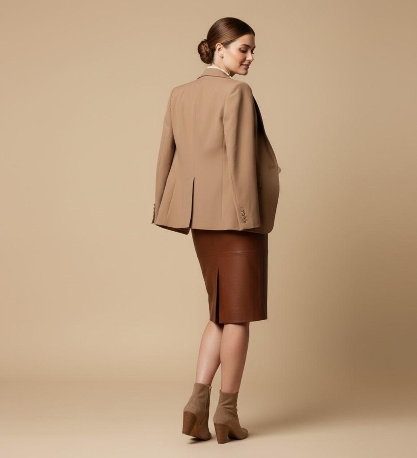 Woman wearing a brown suit with a skirt on a beige background