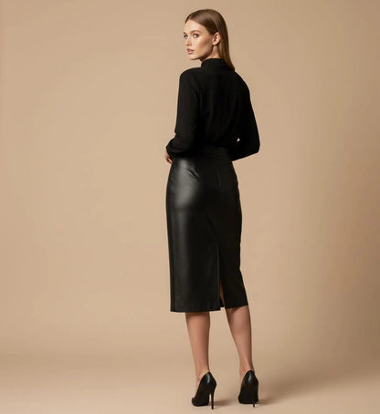 Woman wearing a black leather skirt and black top on a beige background