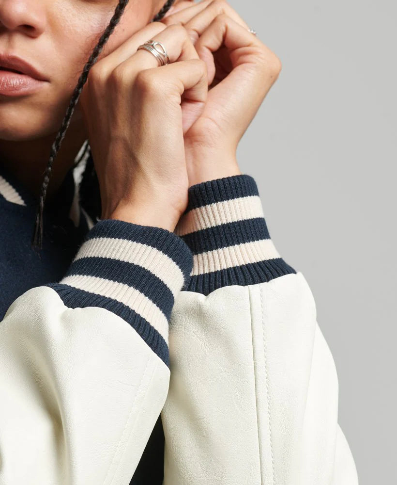Close-up of a person wearing a sweater with striped cuffs on a gray background