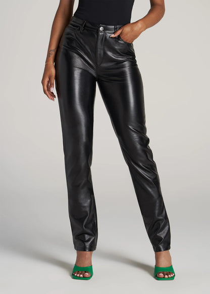 Person wearing black leather pants on a plain background
