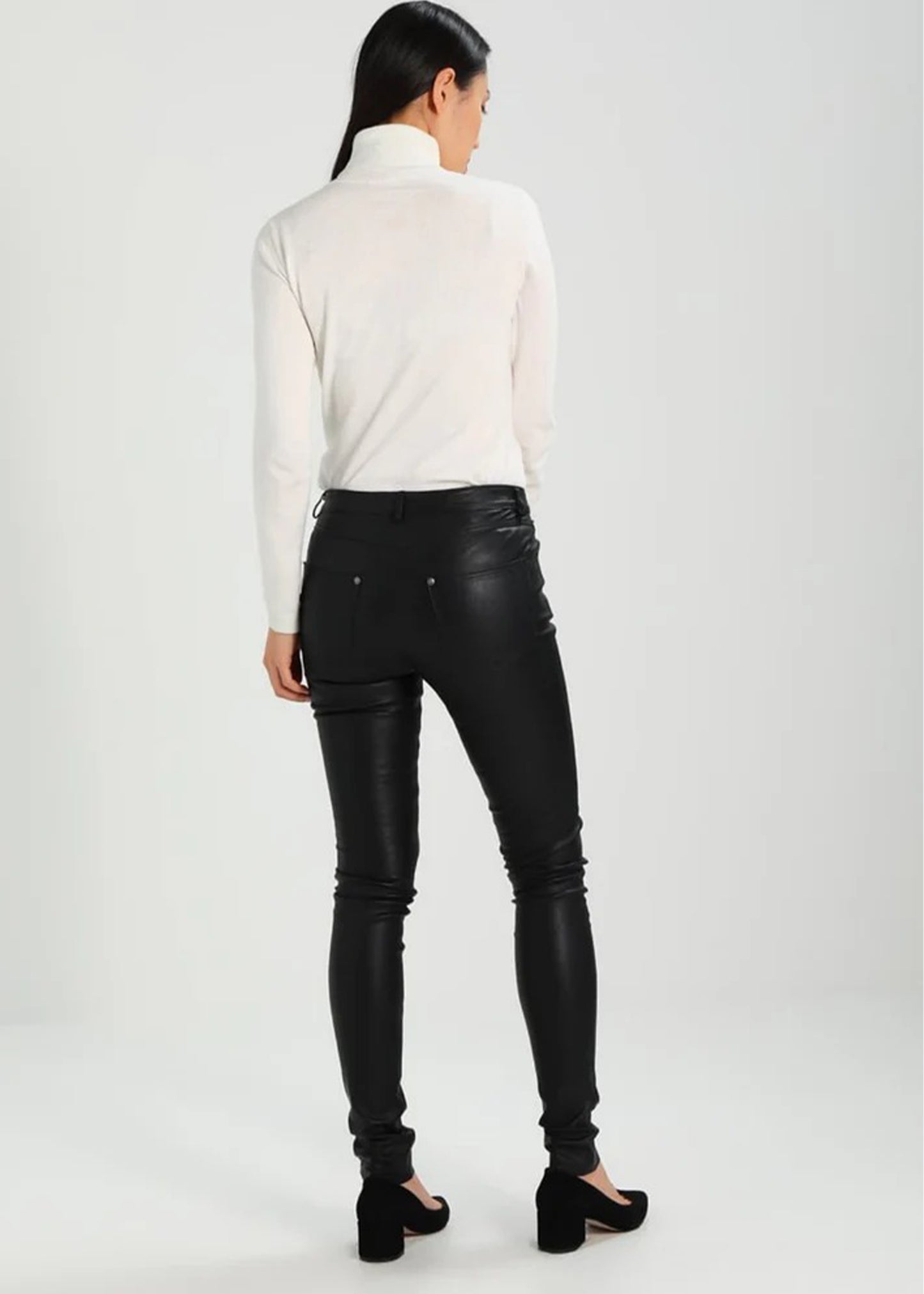 Person wearing black leather pants and a white turtleneck on a white background