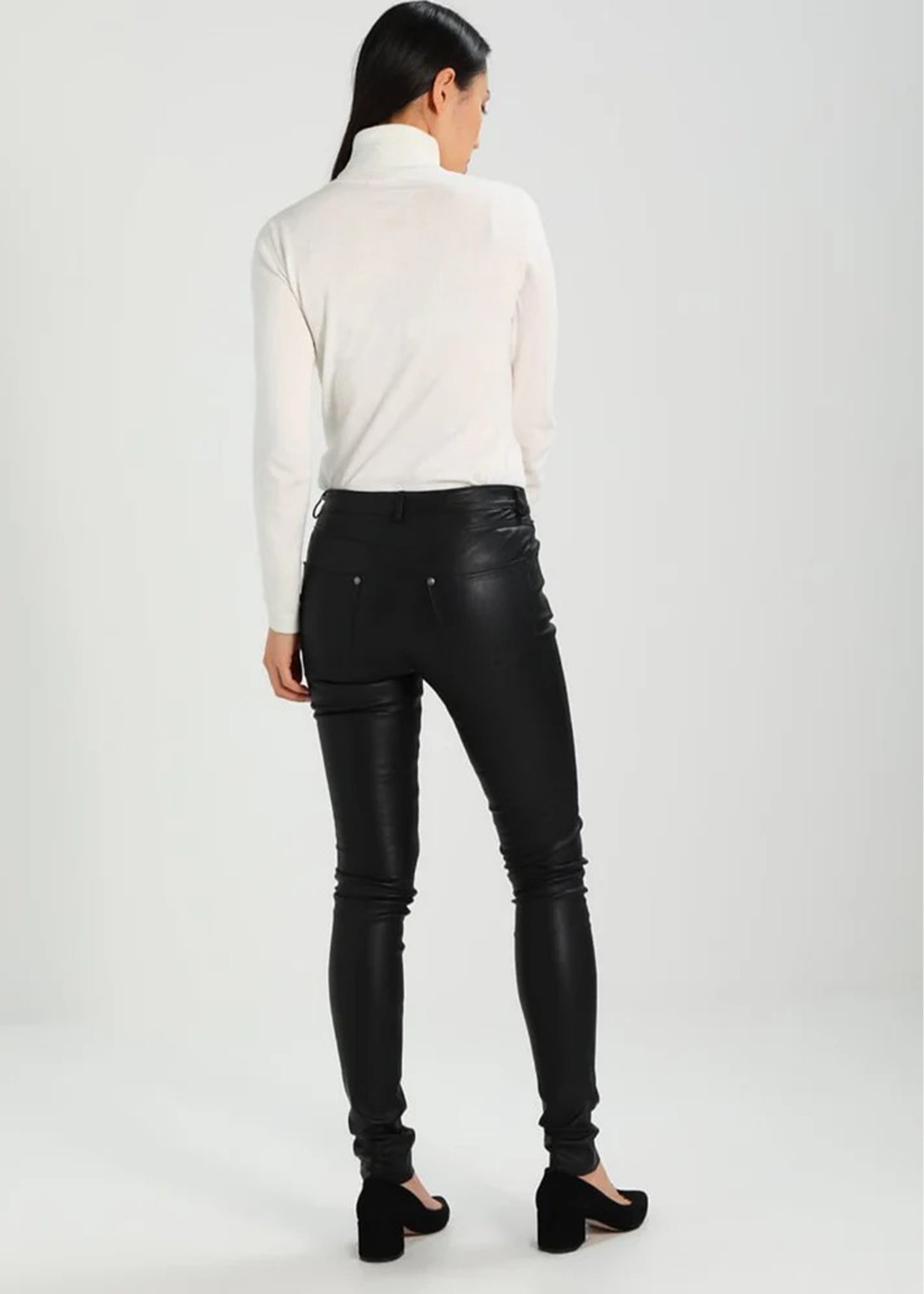 Person wearing black leather pants and a white turtleneck on a white background