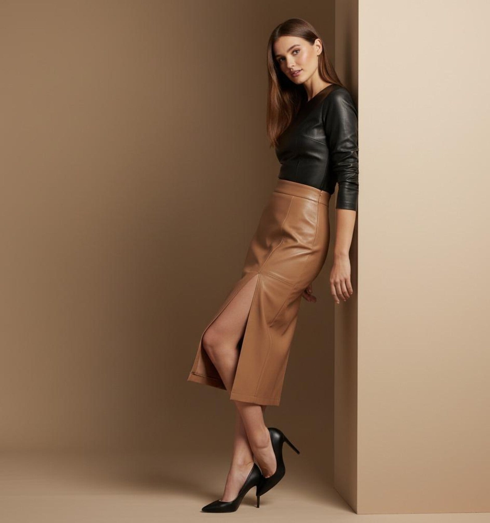 Woman wearing a black leather top and tan leather skirt against a beige background