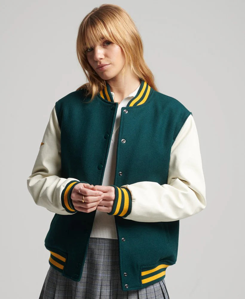 Person wearing a green and white varsity jacket with yellow accents on a gray background