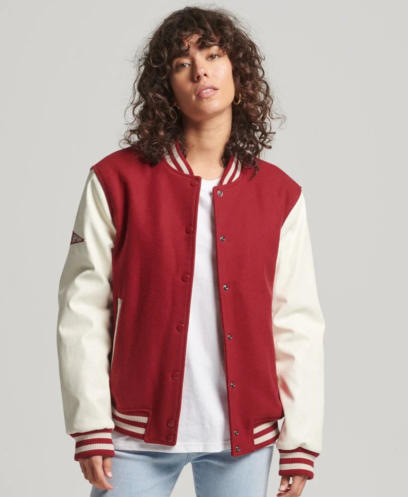 Person wearing a red and white varsity jacket on a plain background