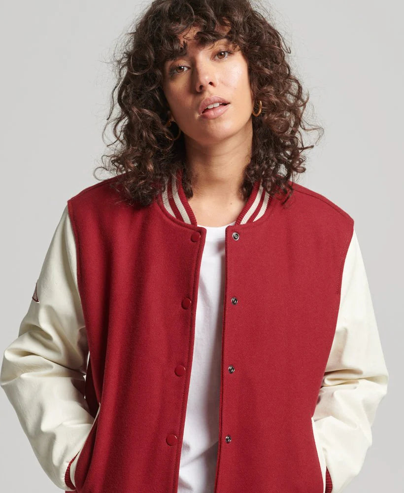 Person wearing a red and cream varsity jacket on a plain background