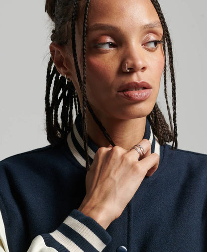 Woman wearing a navy blue jacket with white stripes on a plain background