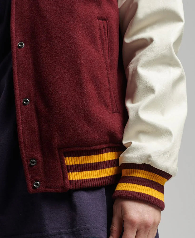 Close-up of a maroon and white varsity jacket with yellow stripes on a neutral background