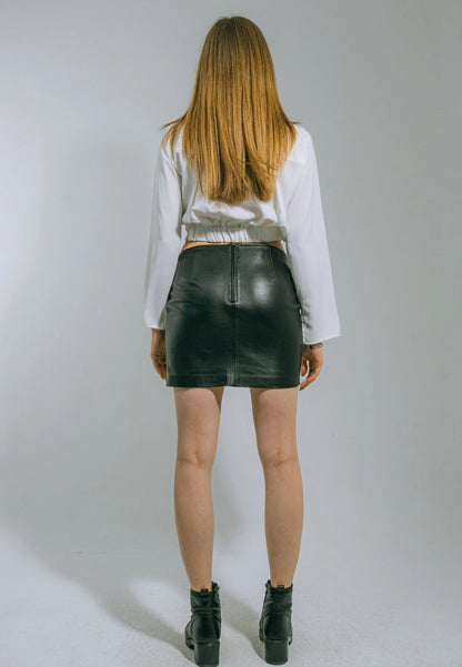 Person wearing a white blouse and black leather skirt on a plain background