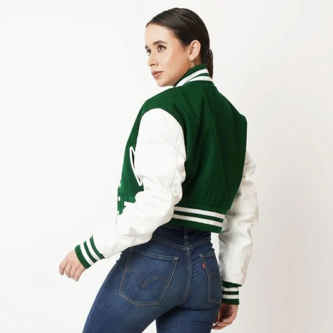 Woman wearing a green and white varsity jacket on a plain background