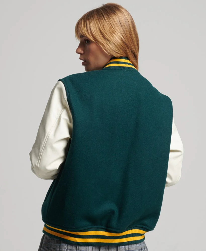 Person wearing a green varsity jacket with white sleeves on a gray background